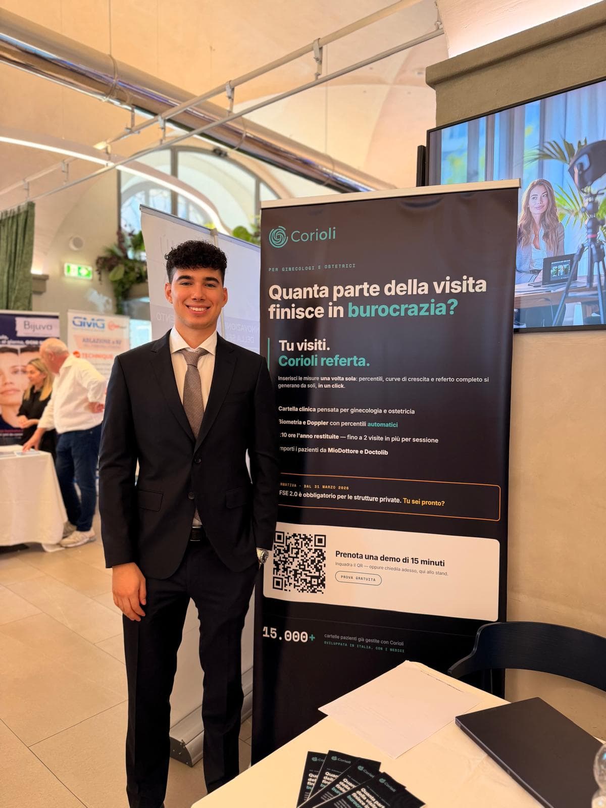 Membro del team Corioli allo stand del congresso, accanto al roll-up dedicato a ginecologi e ostetrici.